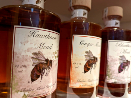Hawthorne mead liquid in bottles stacked on shelves.