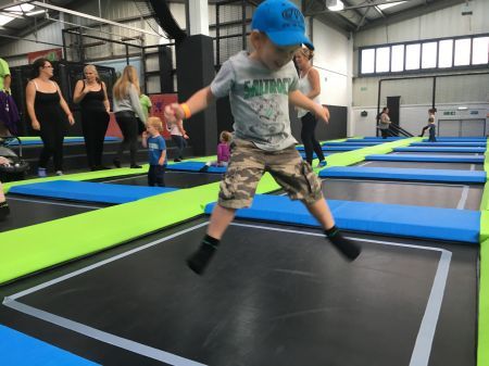 A little boy doing a starjump on the trampoline at sky high