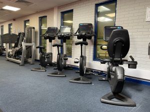 Upstairs gym equipped with variety of exercise machines and free weights.