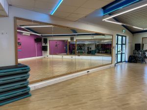 Aerobics studio for exercise classes with mirrored walls and equipped with balls, free weights and resistance bands.
