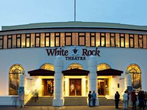 The front entrance of the White Rock Theatre which has three doors and all with steps leading out and then a ramp to the right of the photo