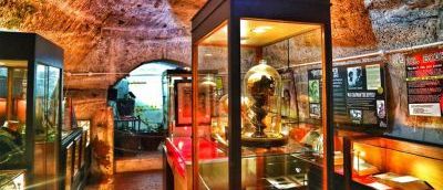 A cave lit up with glass boxes full of artefacts and posters with information for people to read.