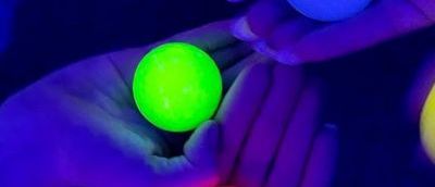 Four hands with four different coloured glow in the dark balls.