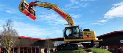 A yellow and red digger on top of a patch of grass.
