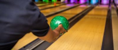 A person throwing a ball down the bowling alley